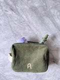 Green toiletry bag with personal care items on a gray marble background