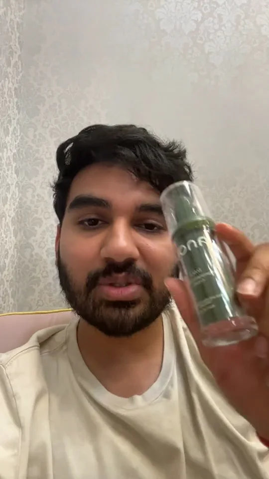 Video still of a man holding a green Dalí bottle beside his face.